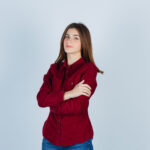 teenage girl in burgundy shirt keeping arms folded and looking confident , front view.